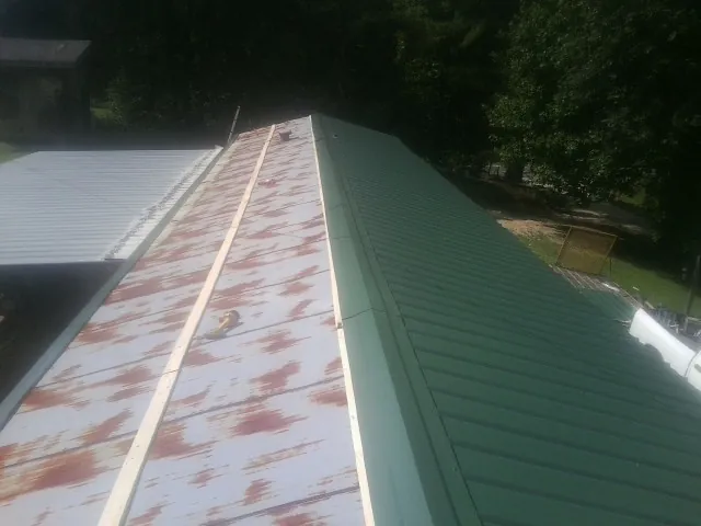 Old rusted panels beside newly installed green metal roofing — Wind Damage Roof Repair by Roofing Brothers in Bloomingdale
