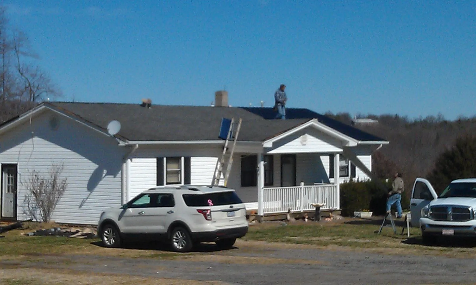Roofers stripping shingles from a white ranch house roof in Bloomingdale