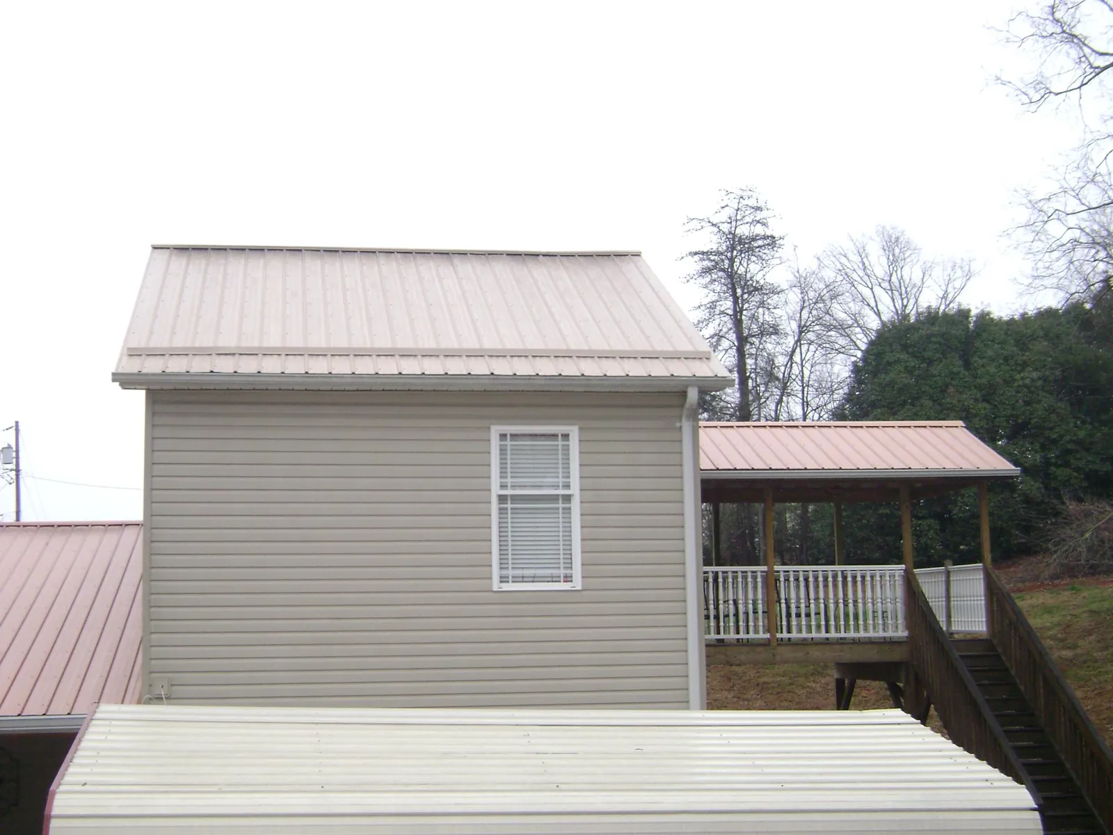 Tan metal roofs on a two story addition and attached porch, from a Roof Replacement job in Bloomingdale